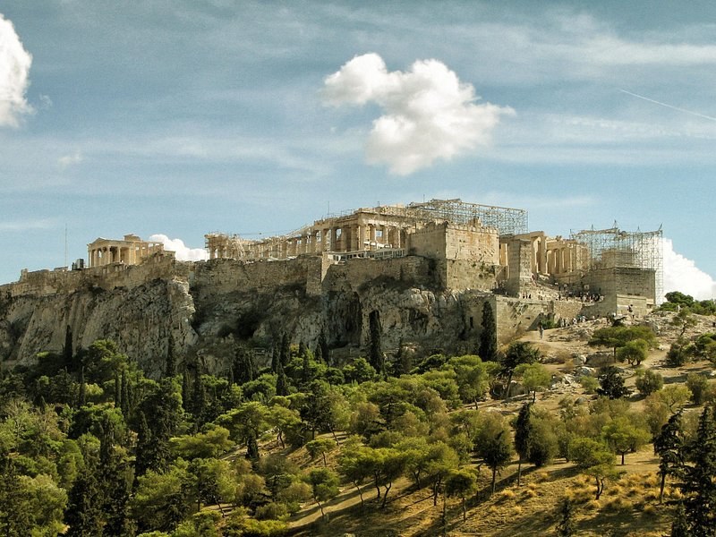 The Acropolis seen across the pine trees of the hills to its south-west, scaffolding on the Propylaea
