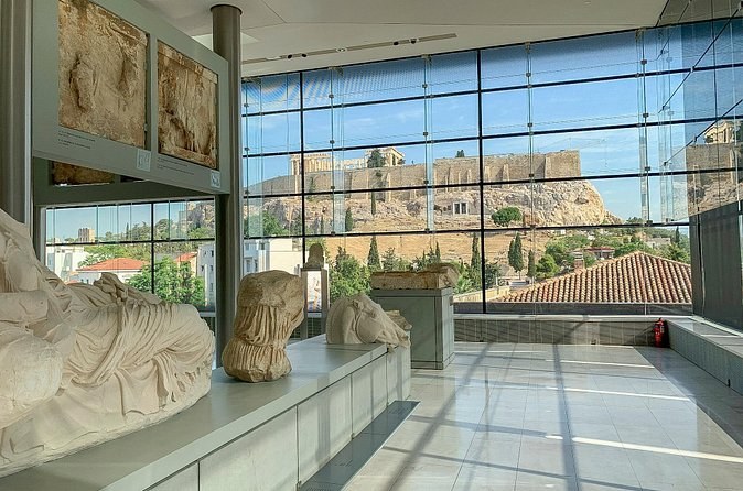 A gallery of the Acropolis Museum, sculpture in the foreground and the rock framed in the glass wall