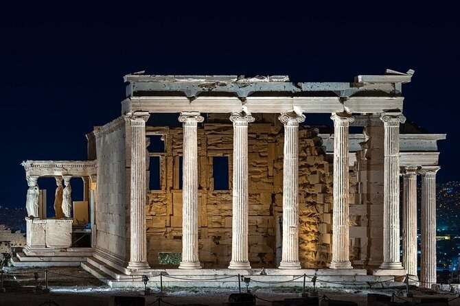 The Erechtheion floodlit against a dark sky, its Ionic columns and the Caryatid porch at the left