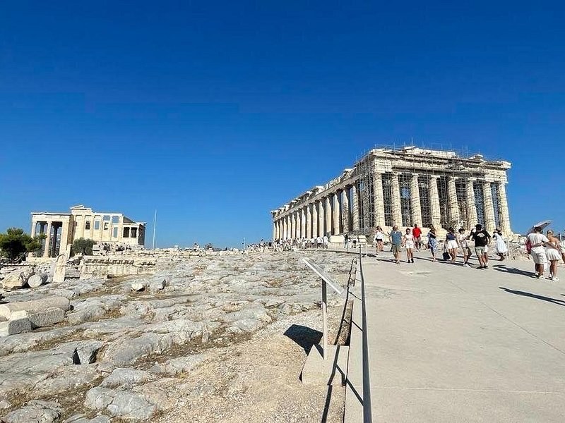 The Parthenon and the Erechtheion across the open plateau of the Acropolis, visitors on the path