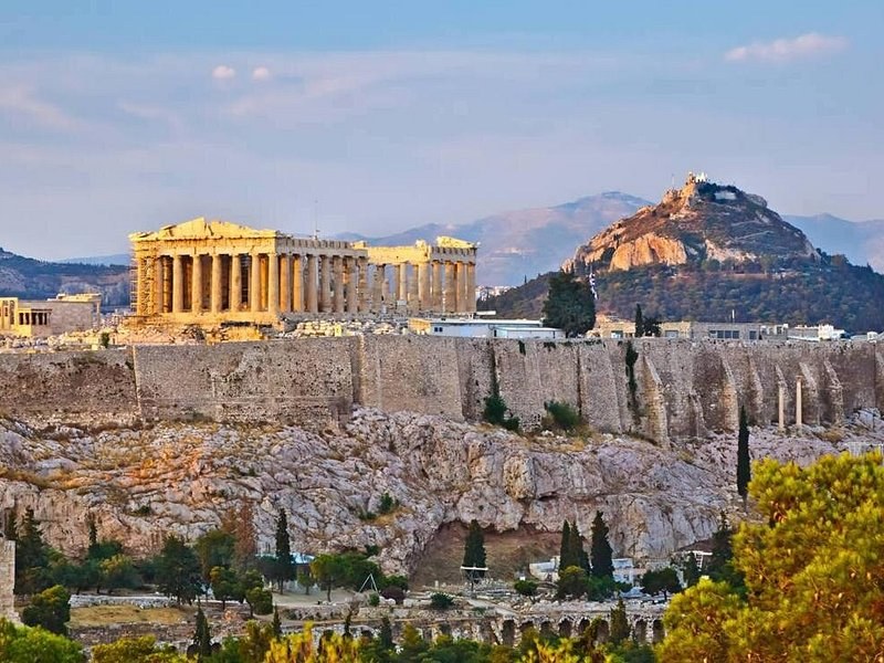 The Parthenon above the Acropolis walls in evening light, Mount Lycabettus behind
