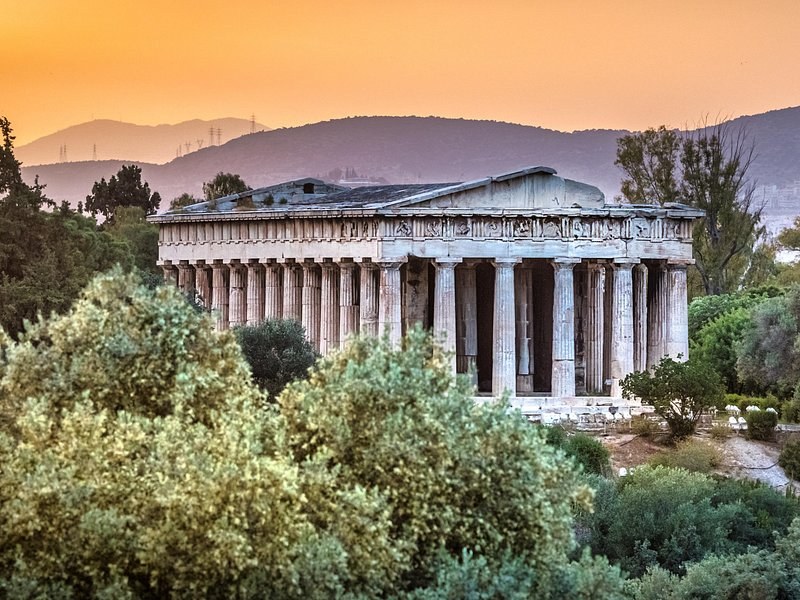 The Temple of Hephaestus above the Ancient Agora, framed by trees at dusk